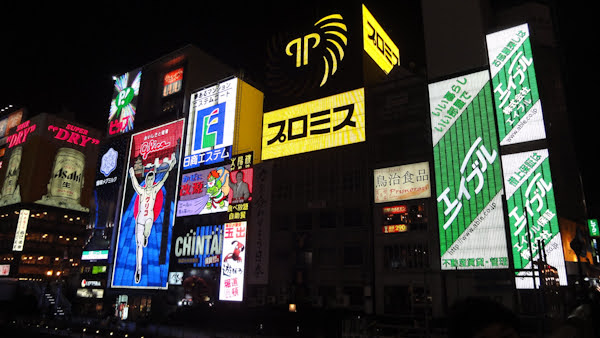 Neon signs in Dotonbori lit up at night, featuring the famous running man with the Glico logo